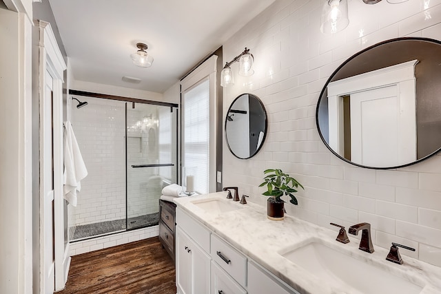 bathroom with hardwood / wood-style floors, tile walls, an enclosed shower, and double sink vanity