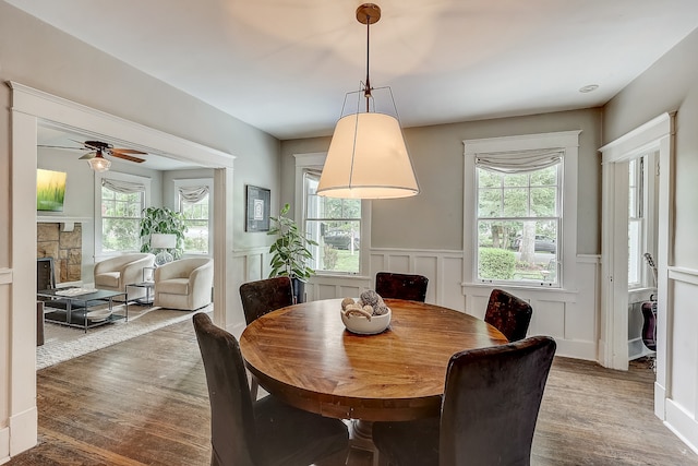 dining area with ceiling fan, a fireplace, and wood-type flooring