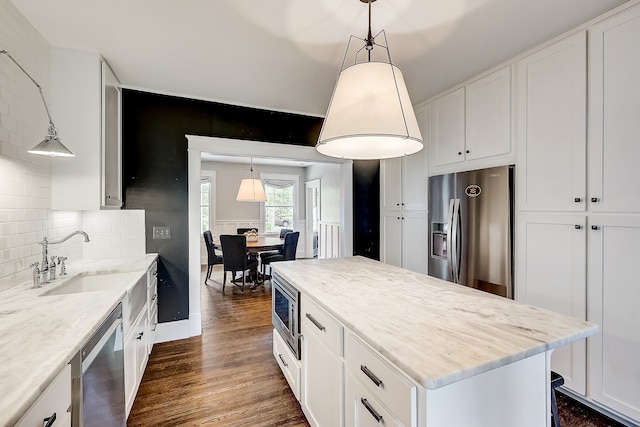 kitchen with pendant lighting, tasteful backsplash, appliances with stainless steel finishes, and dark wood-type flooring