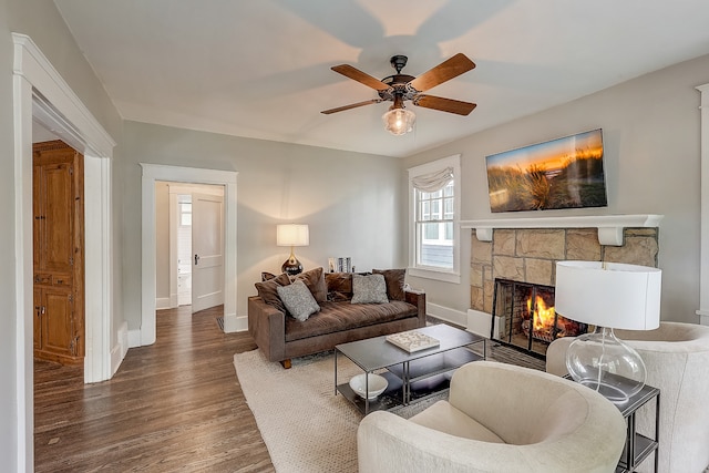 living room featuring ceiling fan, dark wood-type flooring, and a fireplace