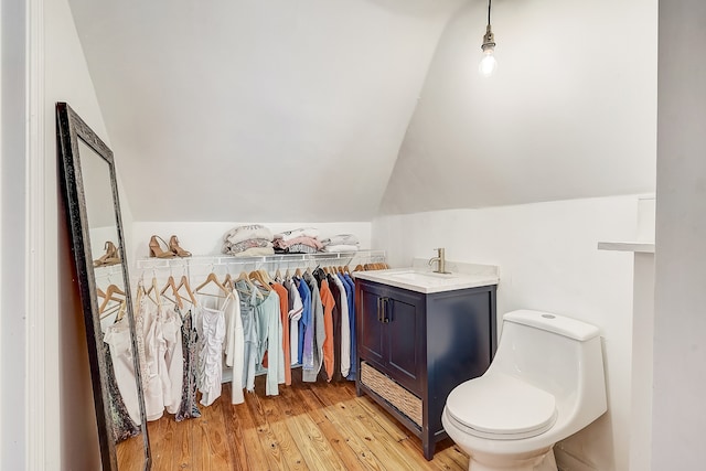 bathroom featuring toilet, vanity, vaulted ceiling, and hardwood / wood-style flooring