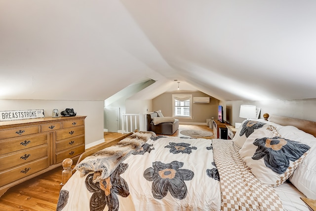 bedroom featuring lofted ceiling, light hardwood / wood-style flooring, and a wall unit AC