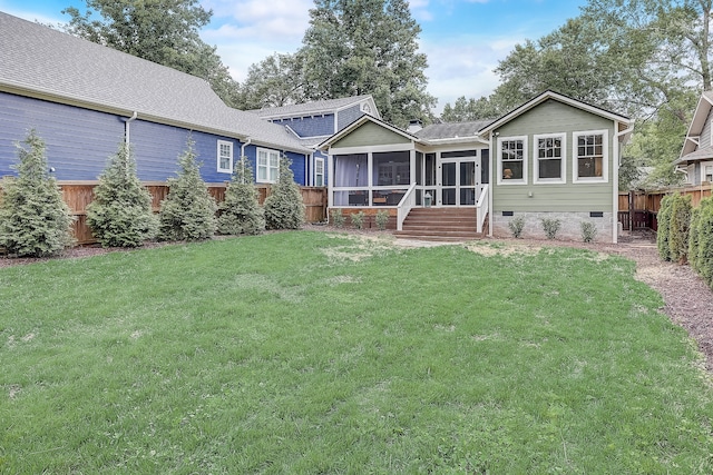 rear view of house featuring a sunroom and a lawn