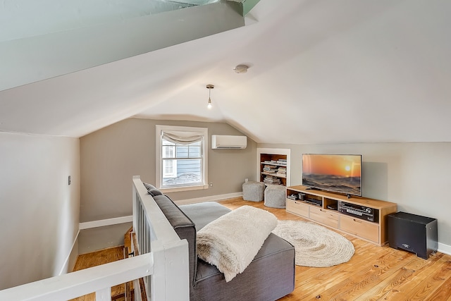 interior space with built in shelves, a wall mounted AC, vaulted ceiling, and light hardwood / wood-style floors