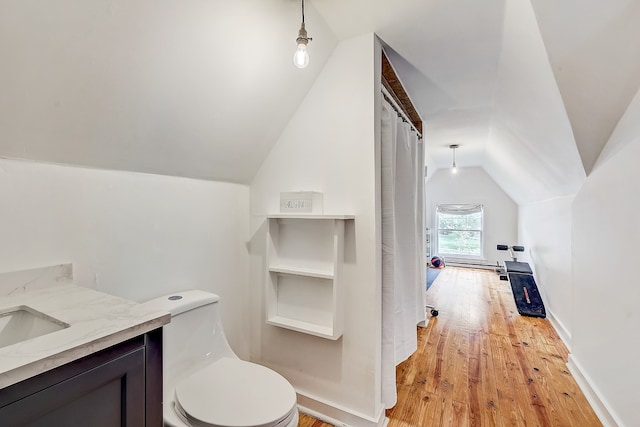 bathroom with toilet, vaulted ceiling, hardwood / wood-style floors, and vanity