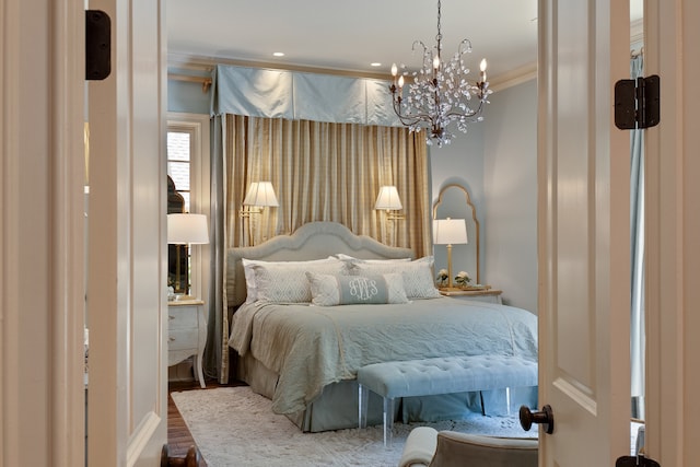 bedroom with an inviting chandelier, ornamental molding, and wood-type flooring