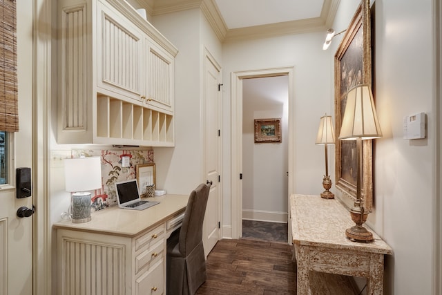 kitchen featuring built in desk, cream cabinets, ornamental molding, and dark wood-type flooring