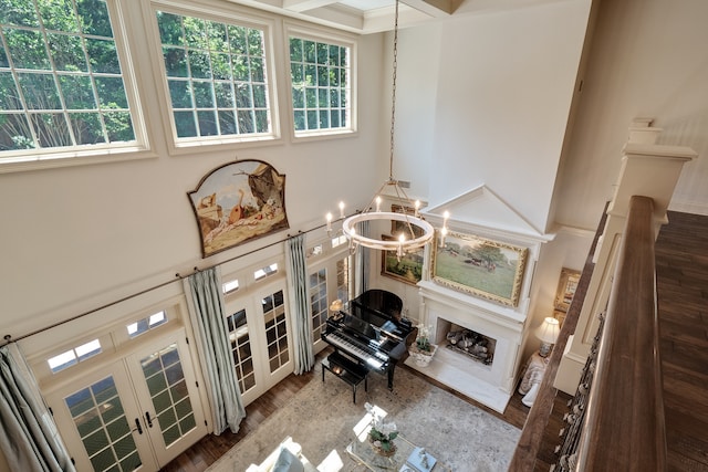 living room with dark wood-type flooring, a chandelier, a towering ceiling, french doors, and ornamental molding