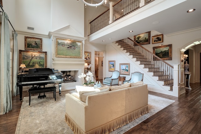 living room featuring crown molding, dark wood-type flooring, and a high ceiling