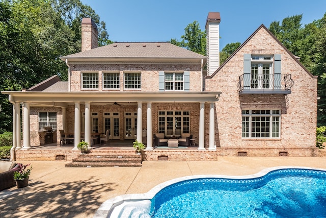 rear view of house with ceiling fan, a balcony, an outdoor hangout area, a patio area, and french doors