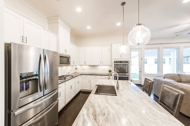 kitchen featuring white cabinets, pendant lighting, backsplash, and stainless steel appliances