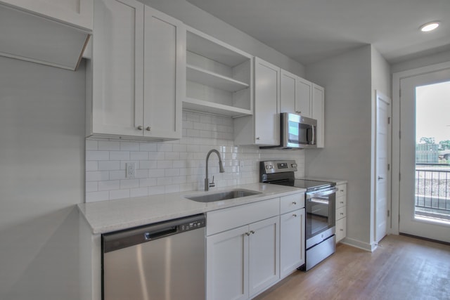 kitchen featuring sink, light stone counters, white cabinets, light hardwood / wood-style flooring, and stainless steel appliances