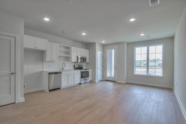 kitchen featuring light hardwood / wood-style floors, white cabinets, stainless steel appliances, backsplash, and sink