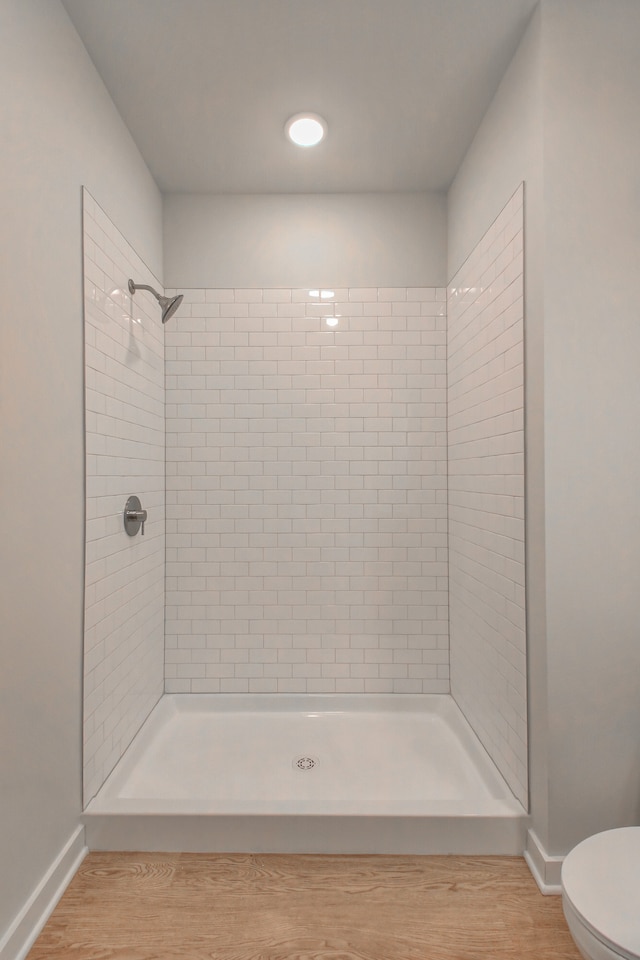 bathroom featuring toilet, hardwood / wood-style floors, and tiled shower