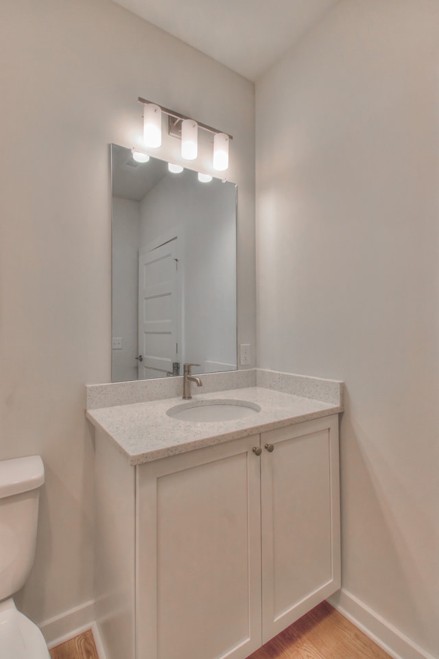 bathroom with toilet, vanity, and wood-type flooring