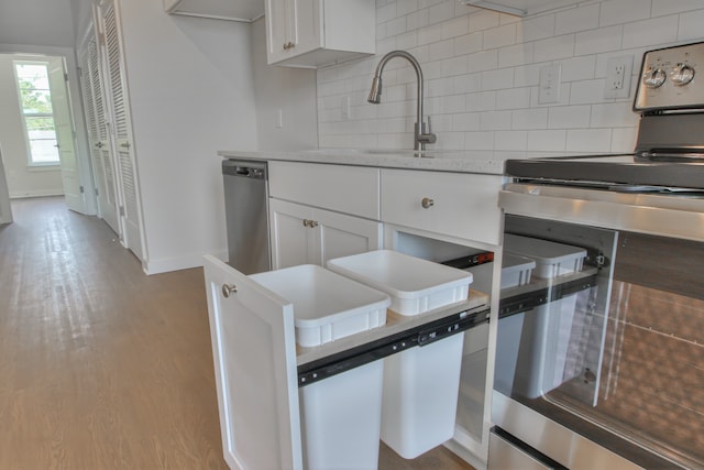 kitchen featuring stainless steel appliances, white cabinets, backsplash, light wood-type flooring, and light stone counters