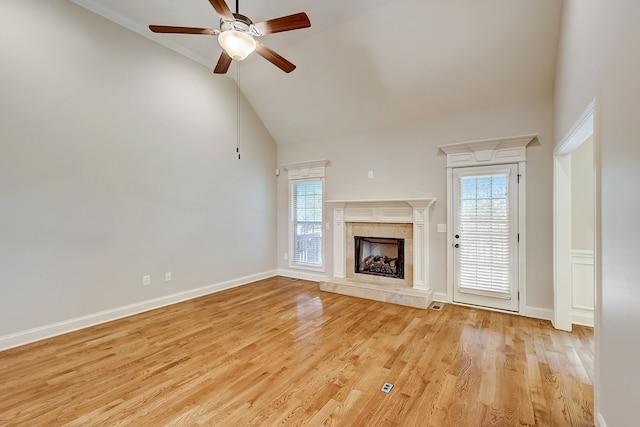 unfurnished living room with high vaulted ceiling, ceiling fan, a wealth of natural light, and light wood-type flooring