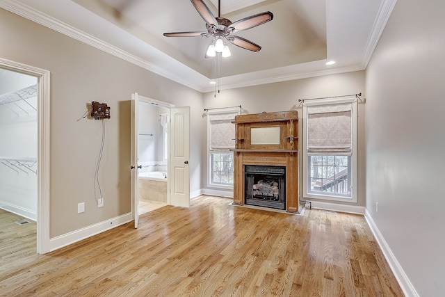 unfurnished living room with light hardwood / wood-style floors, ceiling fan, and a tray ceiling