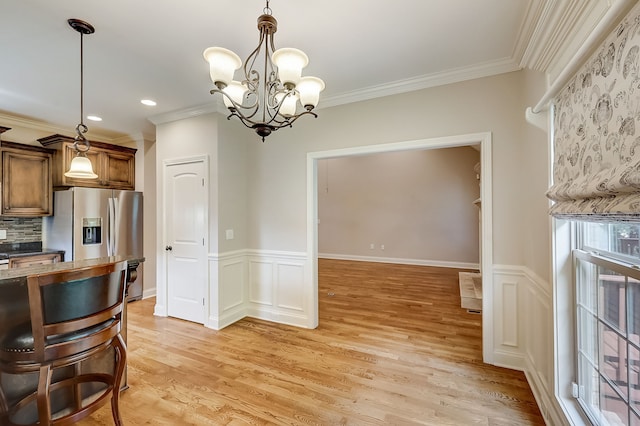 kitchen featuring pendant lighting, tasteful backsplash, light hardwood / wood-style flooring, crown molding, and an inviting chandelier