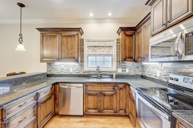 kitchen with hanging light fixtures, stainless steel appliances, backsplash, and light hardwood / wood-style floors