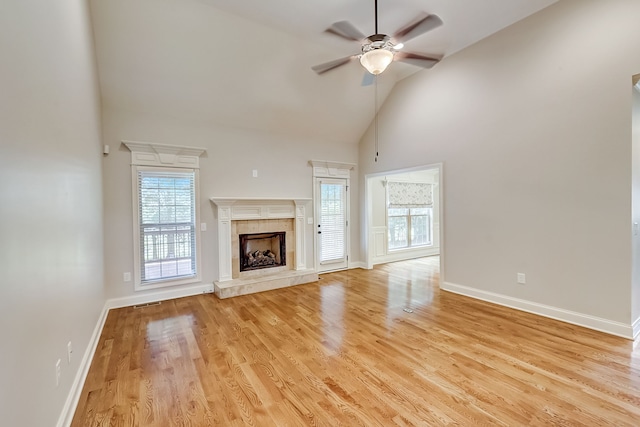 unfurnished living room with a wealth of natural light, ceiling fan, light hardwood / wood-style flooring, and a tiled fireplace