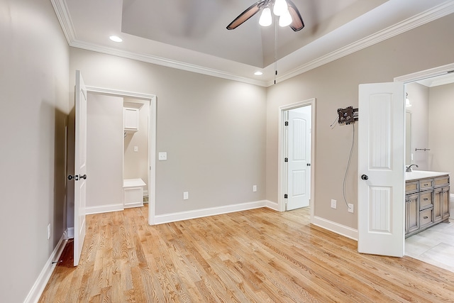 spare room featuring ceiling fan, light hardwood / wood-style flooring, sink, and a tray ceiling