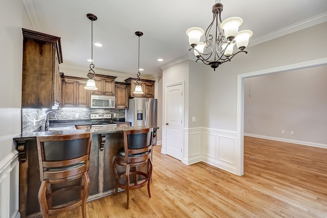 kitchen with pendant lighting, a notable chandelier, appliances with stainless steel finishes, and light hardwood / wood-style flooring