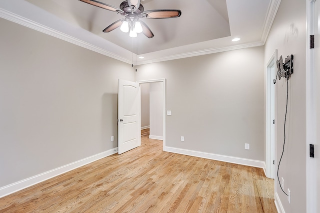 unfurnished room with ceiling fan, crown molding, light wood-type flooring, and a raised ceiling