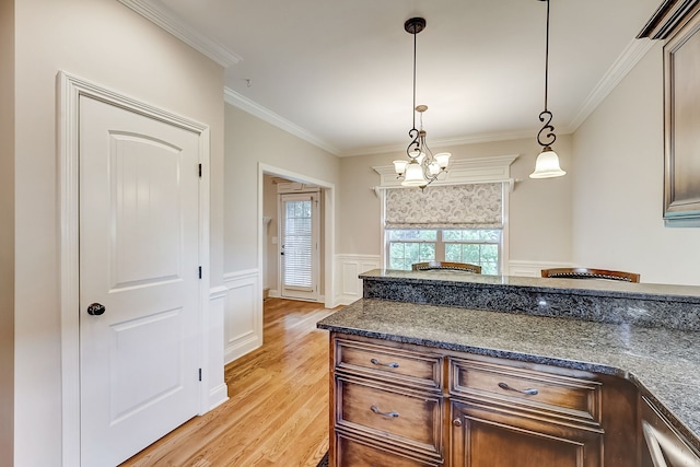 kitchen featuring crown molding, an inviting chandelier, pendant lighting, and light wood-type flooring