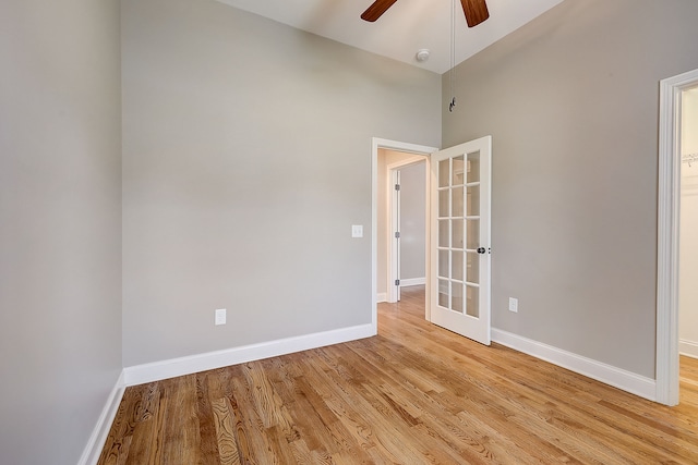 empty room featuring light hardwood / wood-style flooring, ceiling fan, high vaulted ceiling, and french doors