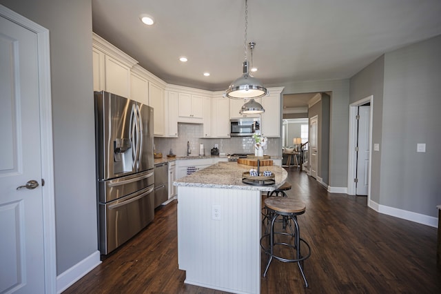 kitchen featuring a kitchen island, decorative light fixtures, tasteful backsplash, appliances with stainless steel finishes, and dark hardwood / wood-style flooring