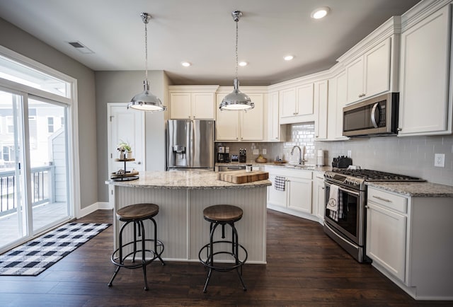 kitchen with hanging light fixtures, stainless steel appliances, backsplash, and dark wood-type flooring