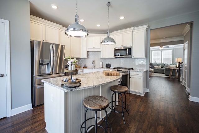 kitchen with a kitchen bar, appliances with stainless steel finishes, backsplash, hanging light fixtures, and dark hardwood / wood-style flooring