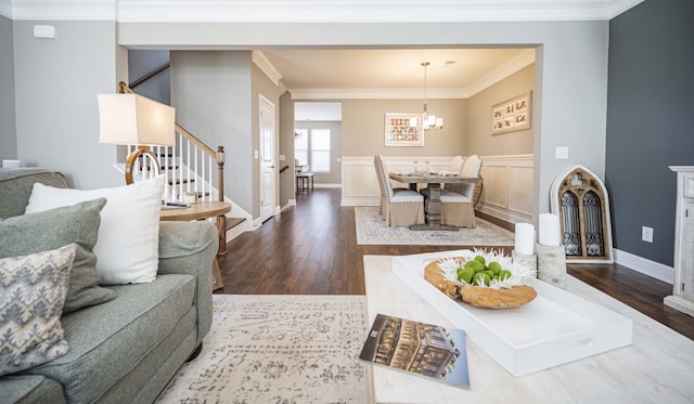 living room featuring dark wood-type flooring, ornamental molding, and a chandelier