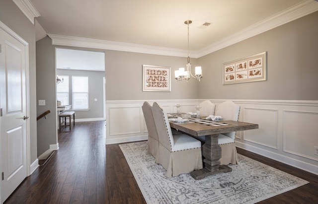 dining space with dark hardwood / wood-style flooring, an inviting chandelier, and crown molding