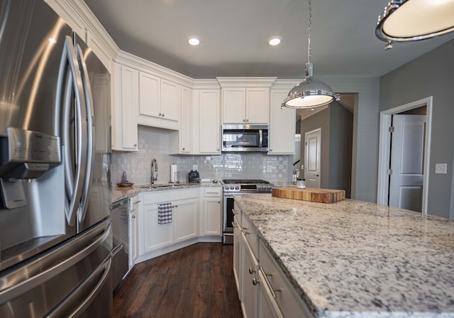 kitchen with light stone countertops, hanging light fixtures, dark hardwood / wood-style floors, sink, and stainless steel appliances