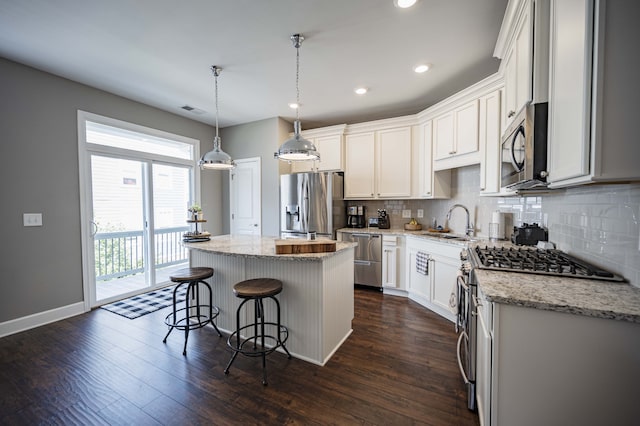 kitchen with hanging light fixtures, backsplash, dark hardwood / wood-style floors, stainless steel appliances, and a kitchen island