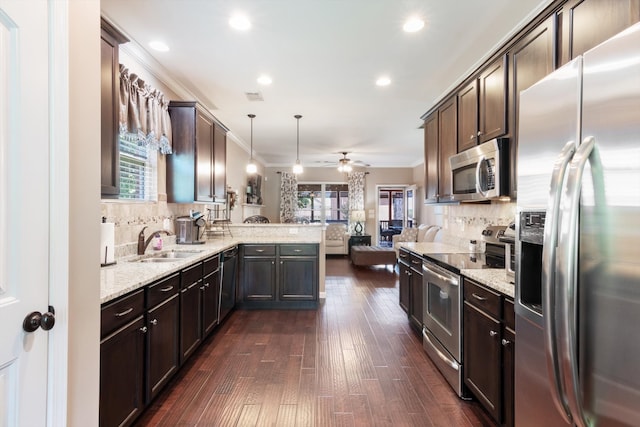 kitchen featuring dark wood-type flooring, appliances with stainless steel finishes, kitchen peninsula, ceiling fan, and ornamental molding