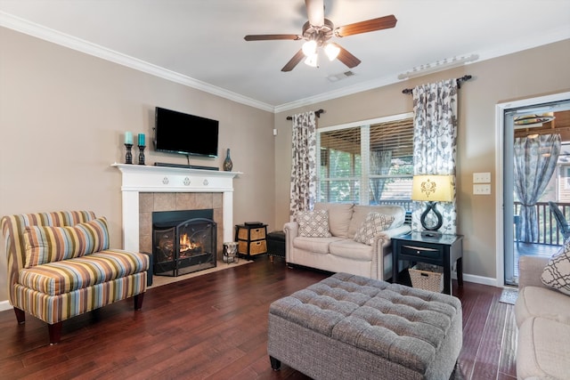 living room with dark hardwood / wood-style flooring, ceiling fan, a tile fireplace, and crown molding