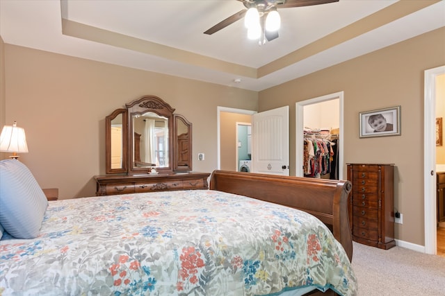 carpeted bedroom featuring a walk in closet, ceiling fan, a closet, washer / clothes dryer, and a raised ceiling