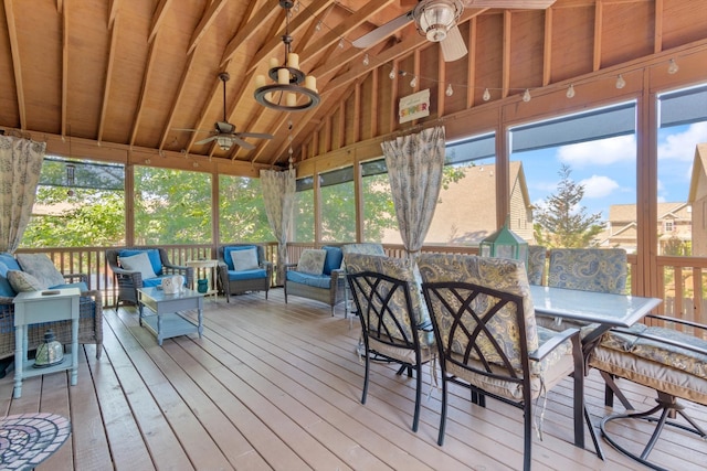 sunroom featuring ceiling fan with notable chandelier and vaulted ceiling