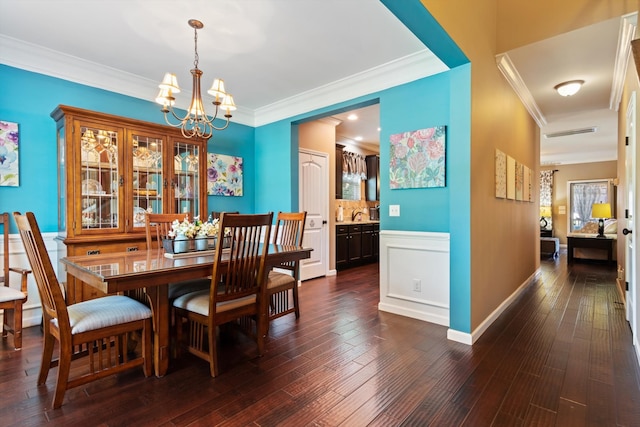 dining room with an inviting chandelier, ornamental molding, and dark hardwood / wood-style floors