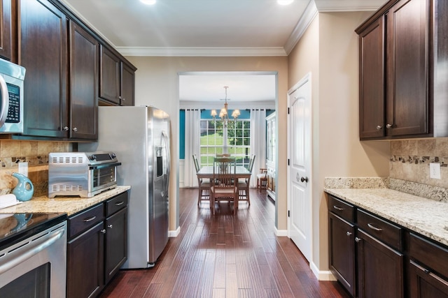 kitchen with a chandelier, backsplash, light stone countertops, and hanging light fixtures