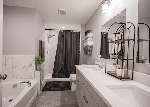 bathroom with toilet, dual vanity, a washtub, a textured ceiling, and tile floors