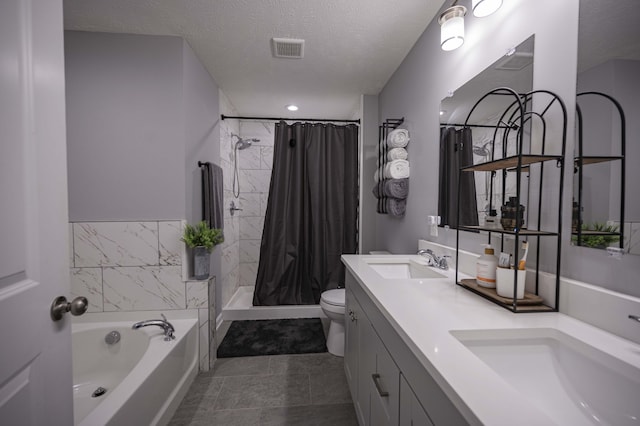 bathroom with toilet, a textured ceiling, a bath, dual bowl vanity, and tile flooring