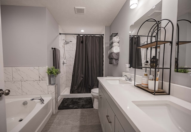 full bathroom featuring toilet, vanity with extensive cabinet space, tile floors, dual sinks, and a textured ceiling