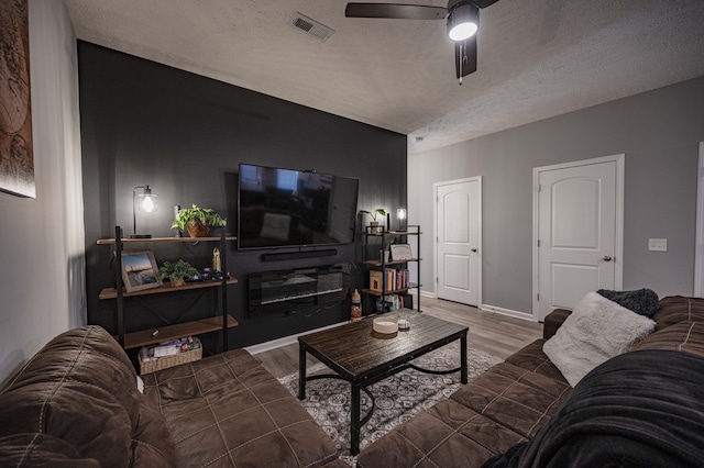 living room with dark hardwood / wood-style flooring, a textured ceiling, and ceiling fan