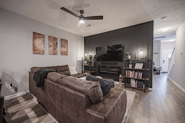 living room featuring ceiling fan, hardwood / wood-style floors, and a textured ceiling