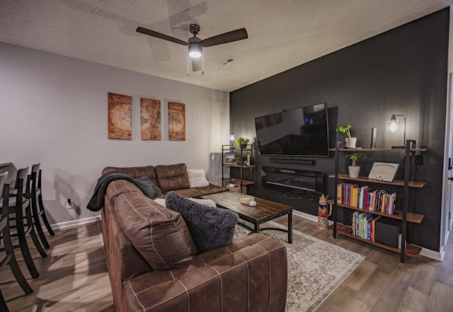 living room with a textured ceiling, dark hardwood / wood-style floors, and ceiling fan