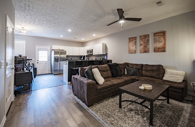 tiled living room featuring a textured ceiling, ceiling fan, and sink